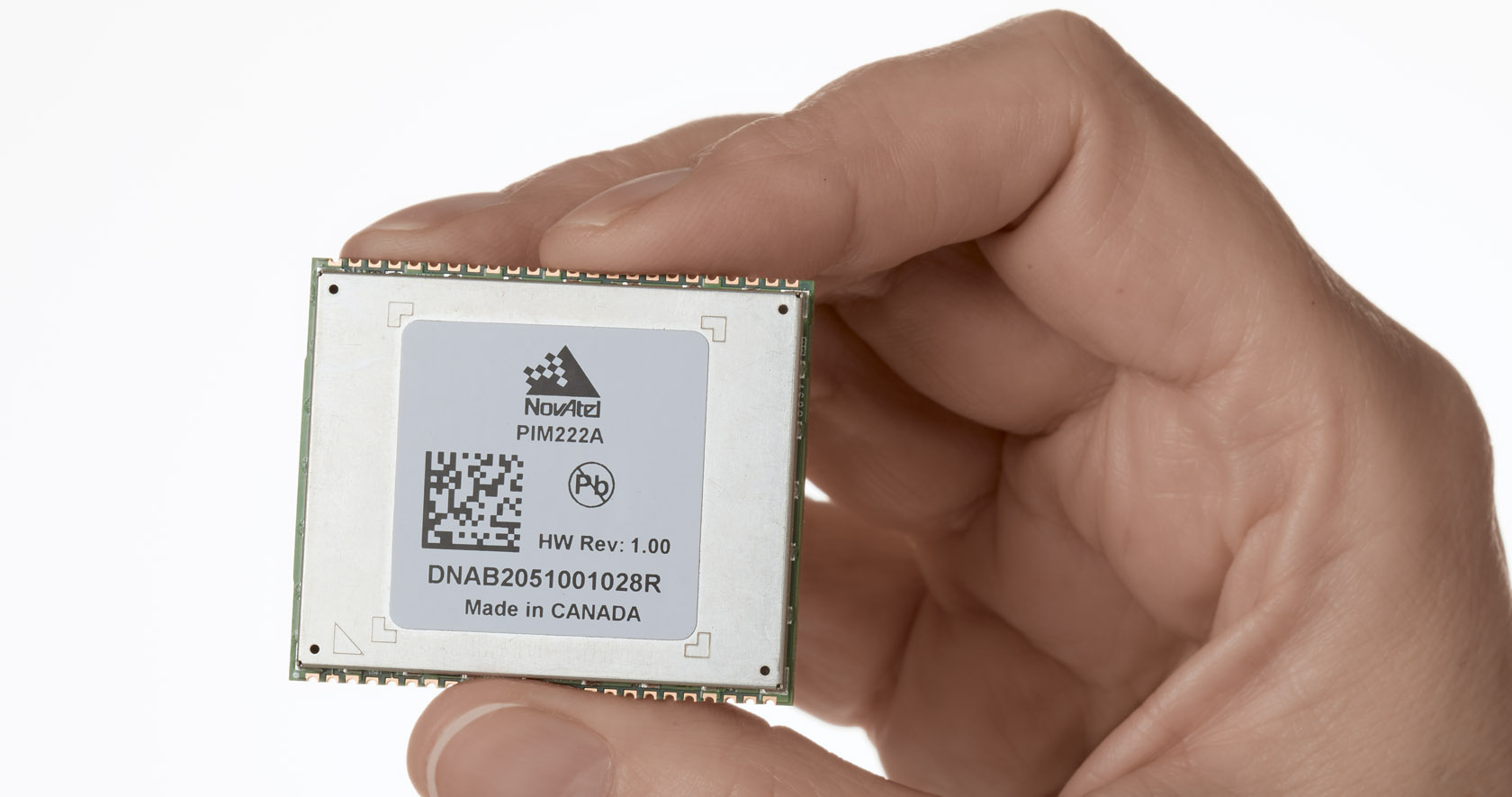 PIM222A solder-down module for ADAS and autonomy from NovAtel in between the thumb and fingers of a hand